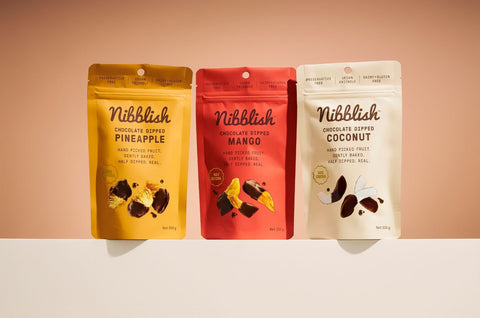 Three packages of Nibblish snacks on a peach background